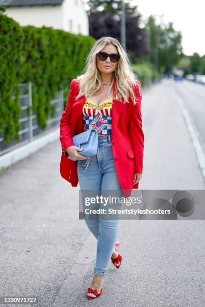 Host Alessandra Geissel wearing a red blazer by Dolce & Gabbana, light blue skinny denim jeans pants by Zara, a multicolored Carretto-print charmeuse...