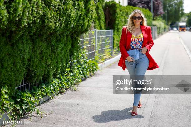 Host Alessandra Geissel wearing a red blazer by Dolce & Gabbana, light blue skinny denim jeans pants by Zara, a multicolored Carretto-print charmeuse...