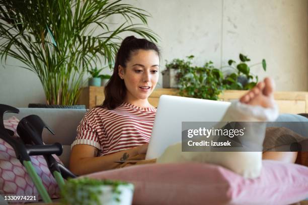 young woman with broken leg at home - orthopedic cast stock pictures, royalty-free photos & images