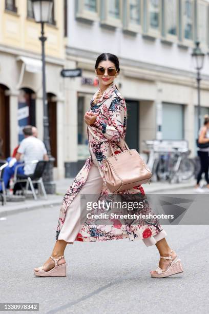 Influencer Jeannette Graf wearing a multicolored long button down shirt dress with floral and bird print by an an londree, pastel pink wide leg pants...