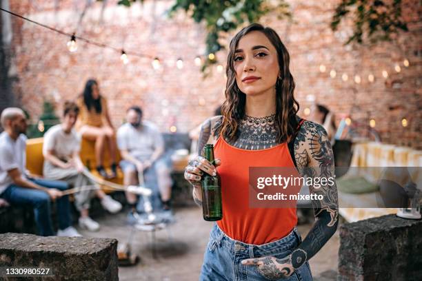 joven tatuada con botella de cerveza en la fiesta del jardín - tattoo fotografías e imágenes de stock