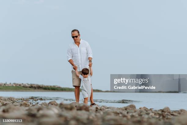 family walking on the beach sand. - uncle nephew stock pictures, royalty-free photos & images