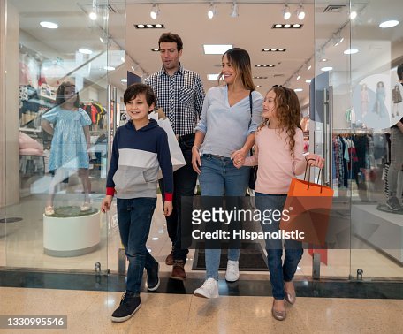 Feliz Familia Comprando Ropa Para Los Niños En El Centro Comercial Foto stock - Getty