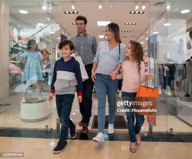 happy family buying clothes for the kids at the shopping center - leaving store stock pictures, royalty-free photos & images