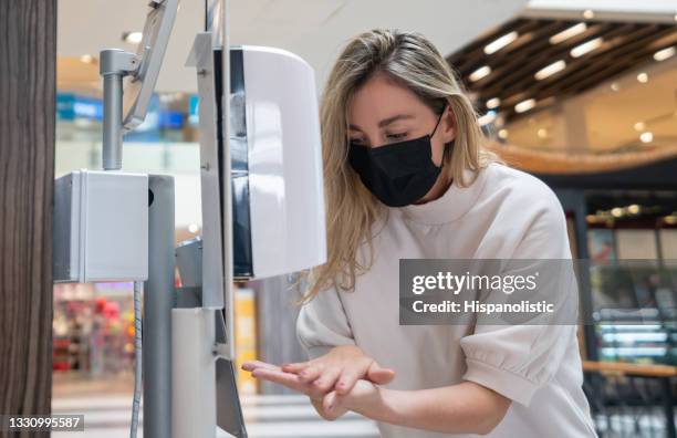 mulher fazendo compras no shopping durante a pandemia e desinfetando as mãos com desinfetante para as mãos - hand sanitiser - fotografias e filmes do acervo