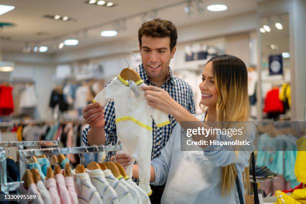 happy pregnant couple buying clothes for their baby - baby boutique stock pictures, royalty-free photos & images