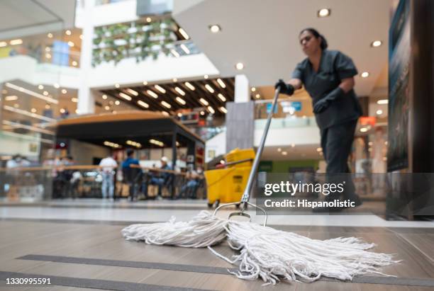 cleaning lady mopping the floor at a shopping center - opgepast-gladde-vloer stockfoto's en -beelden