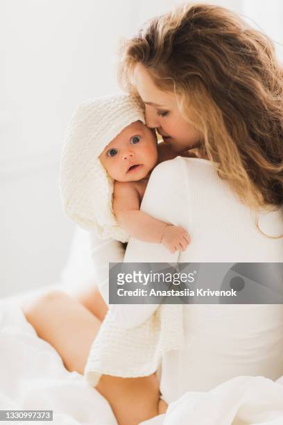 beautiful young mother holding her newborn baby snuggled in a blanket - adults wearing cloth diapers ストックフォトと画像