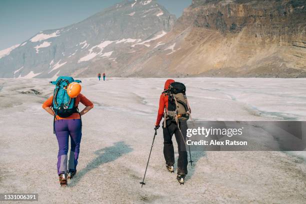 multiple people hike up bare ice on the athabasca glacier in the canadian rockies - people climbing walking mountain group stock pictures, royalty-free photos & images