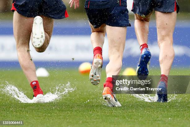 Players warm up in wet conditions during a Melbourne Demons AFL training session at Casey Fields on July 28, 2021 in Melbourne, Australia.