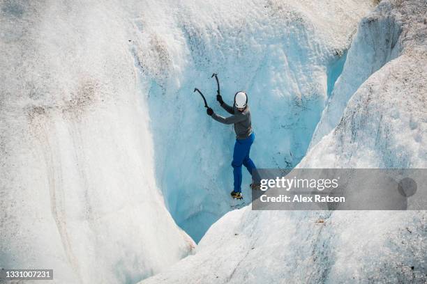 ice climber climbs out fo a crevasse in a canadian rockies glacier - columbia icefield stock pictures, royalty-free photos & images