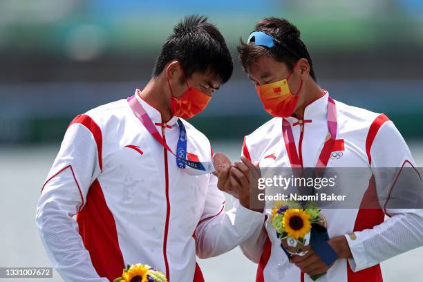 Bronze medalists Zhiyu Liu and Liang Zhang of Team China look at their medals during the medal ceremony for the Men's Double Sculls Final A on day...