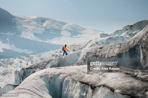 a male mountaineer navigates through a rugged icefall on a glacier - crevasse stock pictures, royalty-free photos & images