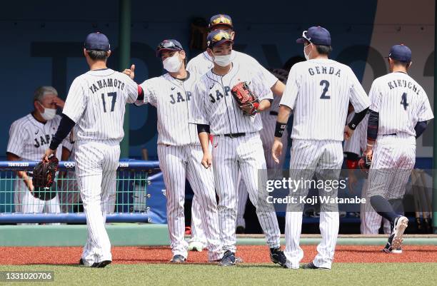 Pitcher Yoshinobu Yamamoto of Team Japan is greeted on his way back to the dugout by a teammate after the second inning against Team Dominican...