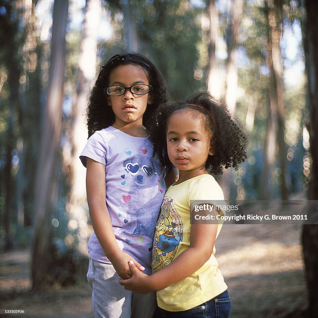 Sister holding hands in front of trees