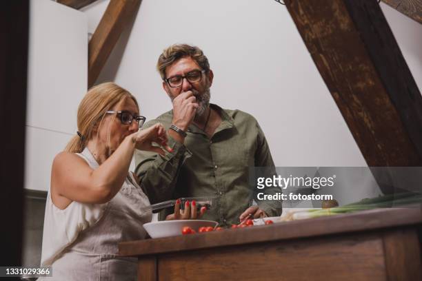 coppia sposata che assaggia le olive mentre prepara la tavola calda - man eating at diner counter foto e immagini stock