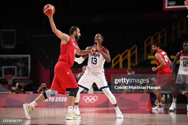 Hamed Haddadi of Team Iran keeps the ball away from Bam Adebayo of Team United States as he looks to pass during a Men's Preliminary Round Group A...