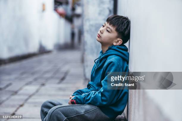 portrait of a young man sitting on street - child abuse stock pictures, royalty-free photos & images