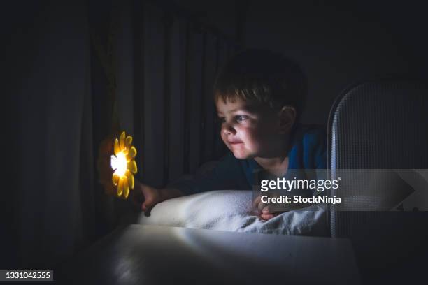 a young boy looks at the light hanging from his bed post. - ninja kid stock pictures, royalty-free photos & images