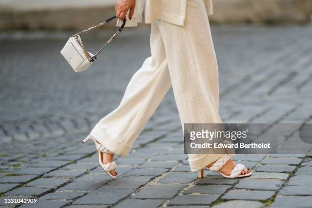 Maria Pasca wears a long white latte sleeveless linen blazer jacket with epaulets / shoulder pads, matching white latte linen flowing pants, a white...