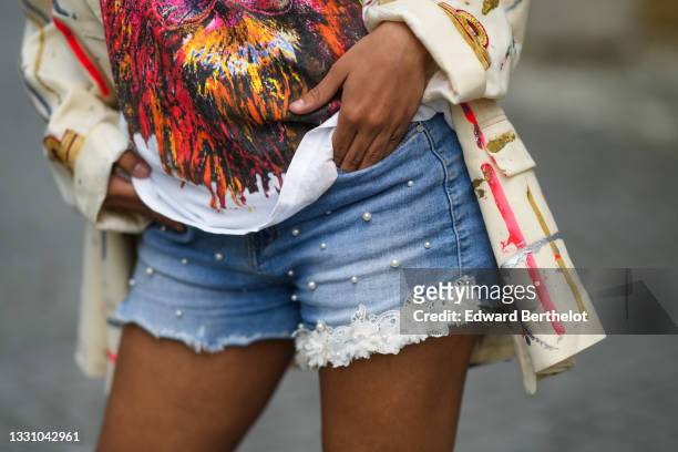 Ines Bensalah wears a white t-shirt with multicolored print pattern , a beige blazer jacket with multicolored painted pattern, blue denim ripped...
