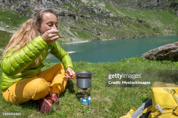 female hiker preparing lunch by the lake - camping stove stock pictures, royalty-free photos & images