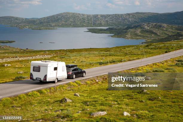 car with a camper trailer on mountain road - summer beitostoelen stock pictures, royalty-free photos & images