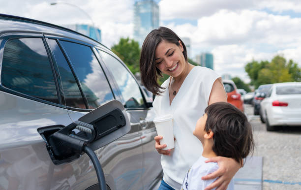 woman and child charging electric car - electric car charging woman stock pictures, royalty-free photos & images