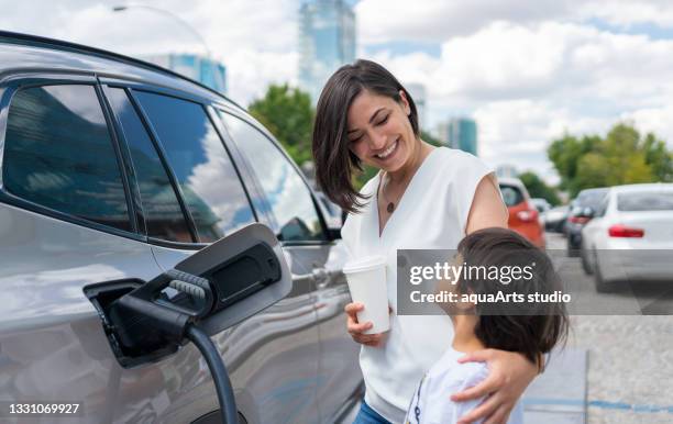 woman and child charging electric car - carro híbrido imagens e fotografias de stock