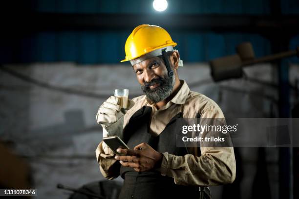 factory worker using mobile phone and drinking tea at workshop - tea processing stock pictures, royalty-free photos & images
