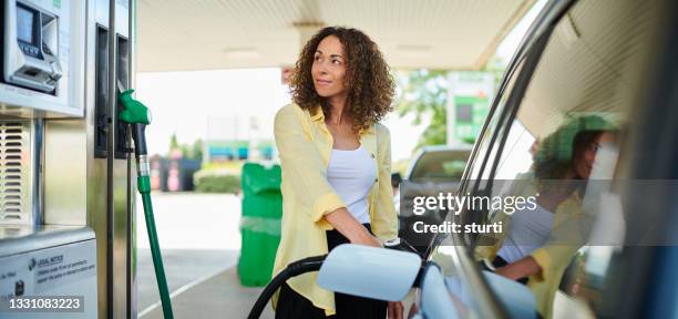 mujer llenando en la gasolinera - garage fotografías e imágenes de stock