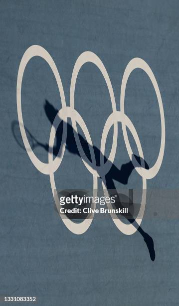 The shadow of Alejandro Davidovich Fokina of Team Spain is on the Olympic rings painted on court as he plays a forehand during his Men's Singles...
