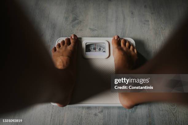 close-up shot of female bare feet standing on weight scale - kilogram stock pictures, royalty-free photos & images