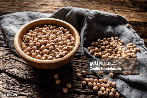 chickpea in a wooden bowl close up on an oak table. - chickpea stock pictures, royalty-free photos & images