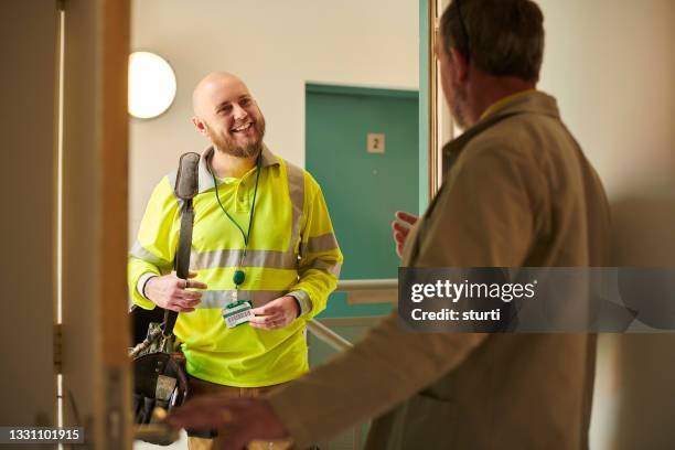 friendly contractor in an apartment block - safety vest stock pictures, royalty-free photos & images