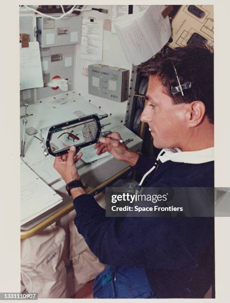 American NASA astronaut Donald A Thomas in the spacelab science module at the Rack 1 Workbench making an observation of one of the newts - smaller...