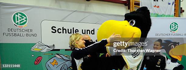 Saskia Bartusiak and Anja Mittag of German Womens National Football team pose with mascot called 'Paule' during the school visit at Pestalozzi school...