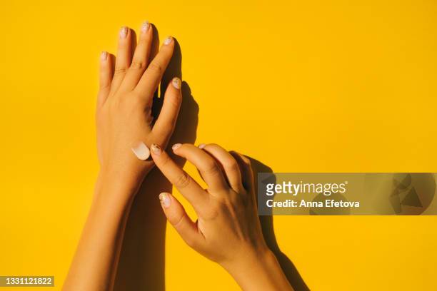 woman is spread cream on hands with manicure against illuminating yellow background. body care concept. trendy colors of the year 2021. flat lay style - coconut oil foto e immagini stock