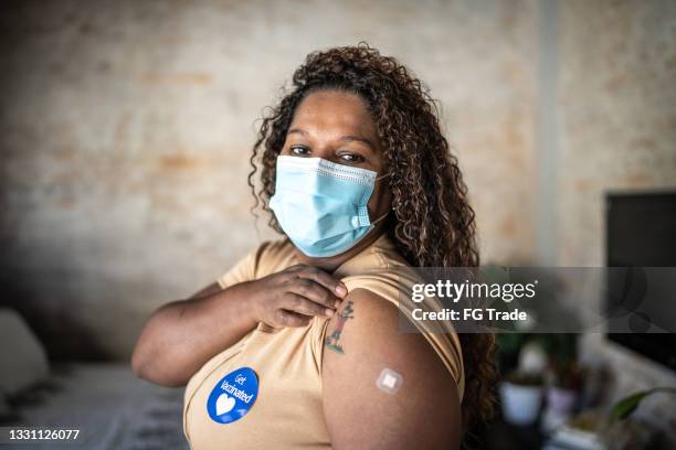 portrait of a mature woman showing arm after vaccination - wearing protective face mask - vaccine sticker stock pictures, royalty-free photos & images
