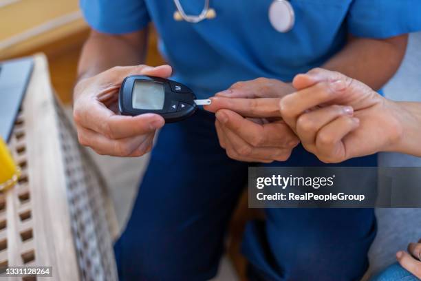 control de la glucosa en sangre en el dedo de la mujer mayor con diabetes - insulina fotografías e imágenes de stock