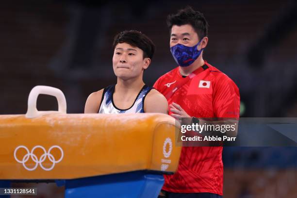 Takeru Kitazono of Team Japan stands with his coach before competing on the pommel horse during the Men's All-Around Final on day five of the Tokyo...