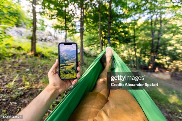 man relaxing in the hammock and using smartphone, personal perspective pov - hammock camping stock pictures, royalty-free photos & images