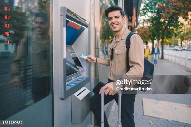 tourist at the atm withdrawing cash with credit card - man atm smile stock pictures, royalty-free photos & images