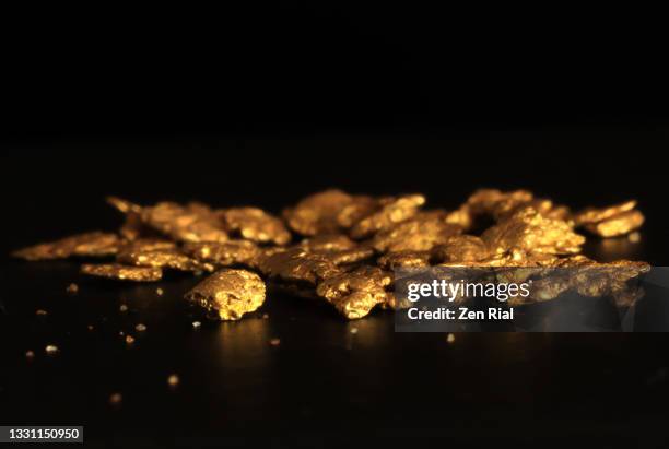 collection of small gold nuggets on black background - gold mining foto e immagini stock