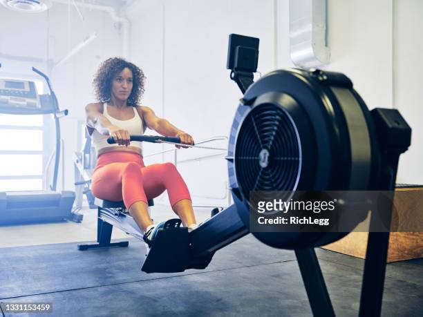 mujer en un gimnasio de entrenamiento cruzado - rowing fotografías e imágenes de stock