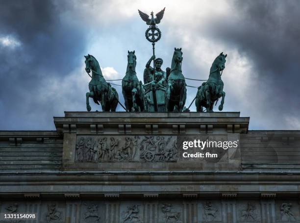 quadriga statue on the brandenburg gate with dramatic sky (berlin, germany) - quadriga statue brandenburg gate stock-fotos und bilder