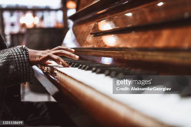 african male gently playing the piano - piano stock pictures, royalty-free photos & images
