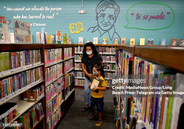 Liliana Real and Giovanni Garcia pick out books at the grand reopening of the Maywood Cesar Chavez Library after pandemic closures and extensive...