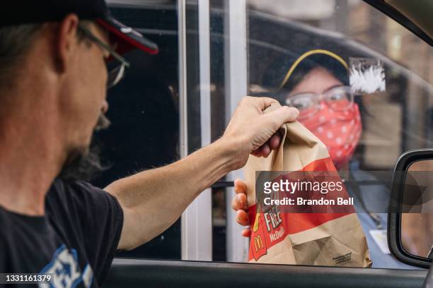 Customer receives his food in a McDonald's drive-thru on July 28, 2021 in Houston, Texas. McDonald's corporation has said that its sales are...