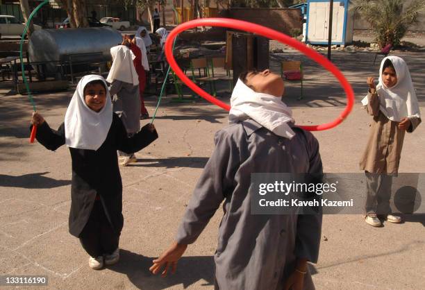 Schoolgirls play in the courtyard of their demolished school 11 months after a major earthquake struck the city, Bam, Iran, 6th November 2004. The...